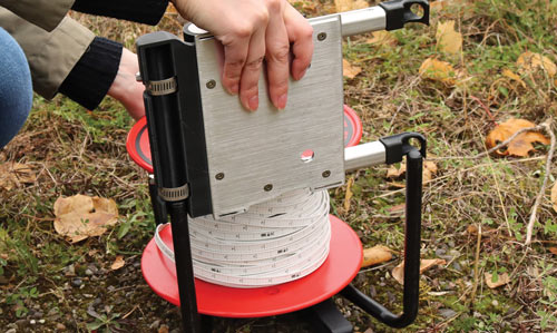 enrollador power winder por las patas de un carrete medidor de nivel de agua de Solinst para colocarlo en la posición correcta y alinear los rodillos con las placas frontales delantera y trasera