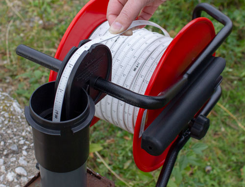 indicador de profundidad y carcasa del pozo solinst que se utiliza en el campo para tomar una lectura de cinta plana marcada con láser