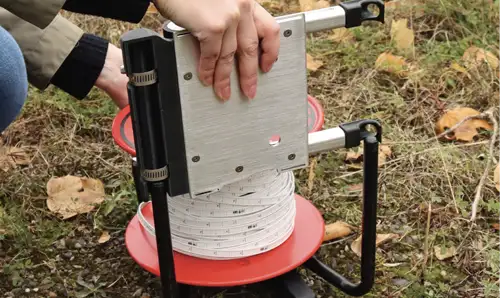 sliding power winder down the legs of a solinst water level meter reel to get it into the right position and align the rollers with the front and back faceplates